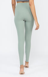 Full-length muted green leggings with high waistband, smooth stretchy fabric on woman.