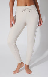 Light beige fleece joggers with drawstring waist and side piping, tapered fit.