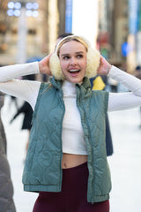 Dark forest green quilted women's vest with high collar, styled over white cropped top.