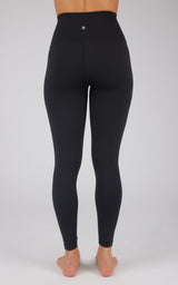 Black super high waist ankle leggings with a smooth, fitted design on a model standing barefoot.
