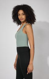 Sleeveless tank top with built-in bra in muted green, fitted silhouette.