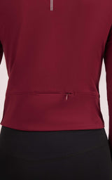 Women's full zip athletic jacket in deep wine red with rear zippered pocket and smooth fabric finish.