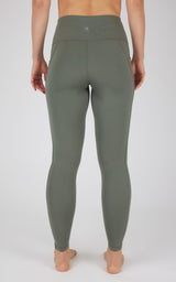 High waist fleece-lined leggings in muted green with flat seams and side pockets, rear view.