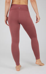 High waist fleece-lined leggings in muted reddish plum with side pockets and flat seams, shown from back.
