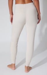 Women's light beige fleece joggers with elastic cuffs and high-rise waistband shown from back.