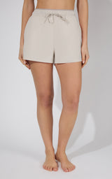 Light beige stretch woven running shorts with adjustable drawstring waist and relaxed fit.