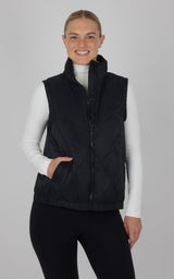 Black quilted sleeveless vest with front zipper and pockets, worn over white turtleneck.
