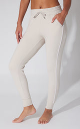 Women's beige fleece joggers with white side piping and adjustable drawstring waistband.