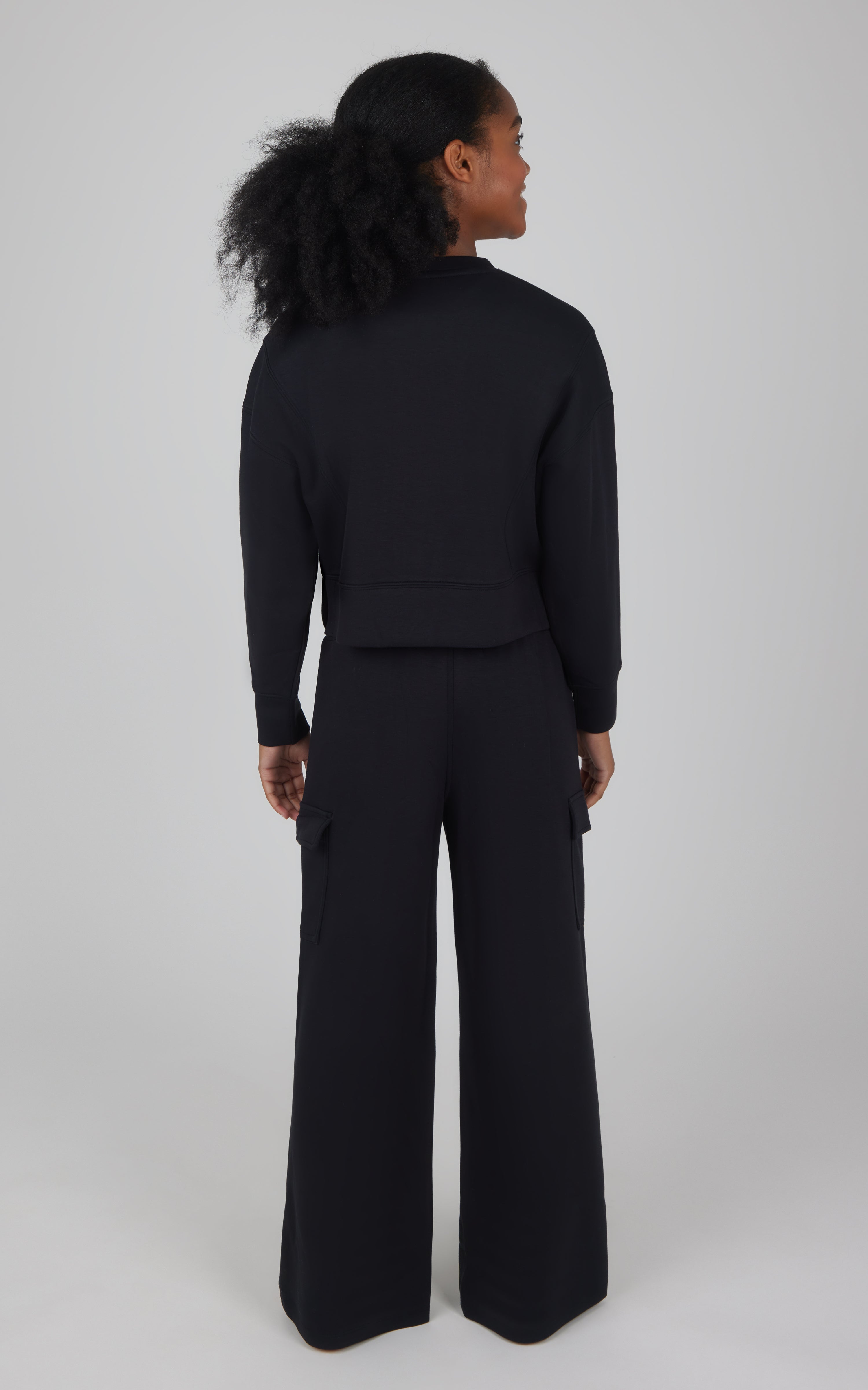 Girls black softlite cropped pullover with matching wide-leg cargo pants, back view.