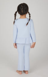 Toddler girl wearing light blue melange pullover top with ruffle hem and matching flare leg pants, back view.