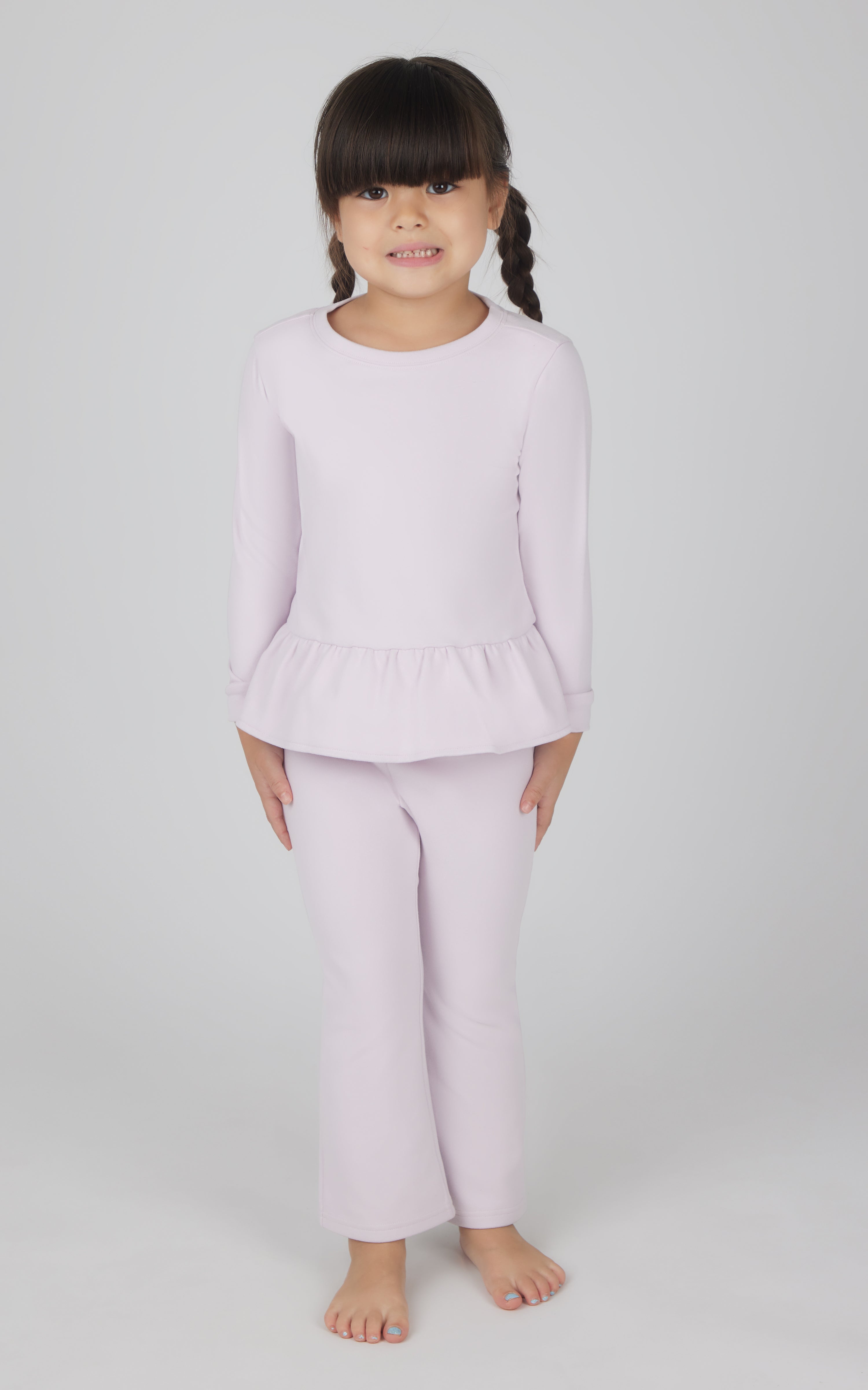 Toddler girl wearing light pink melange long-sleeve pullover with peplum hem and matching flare leg pants.