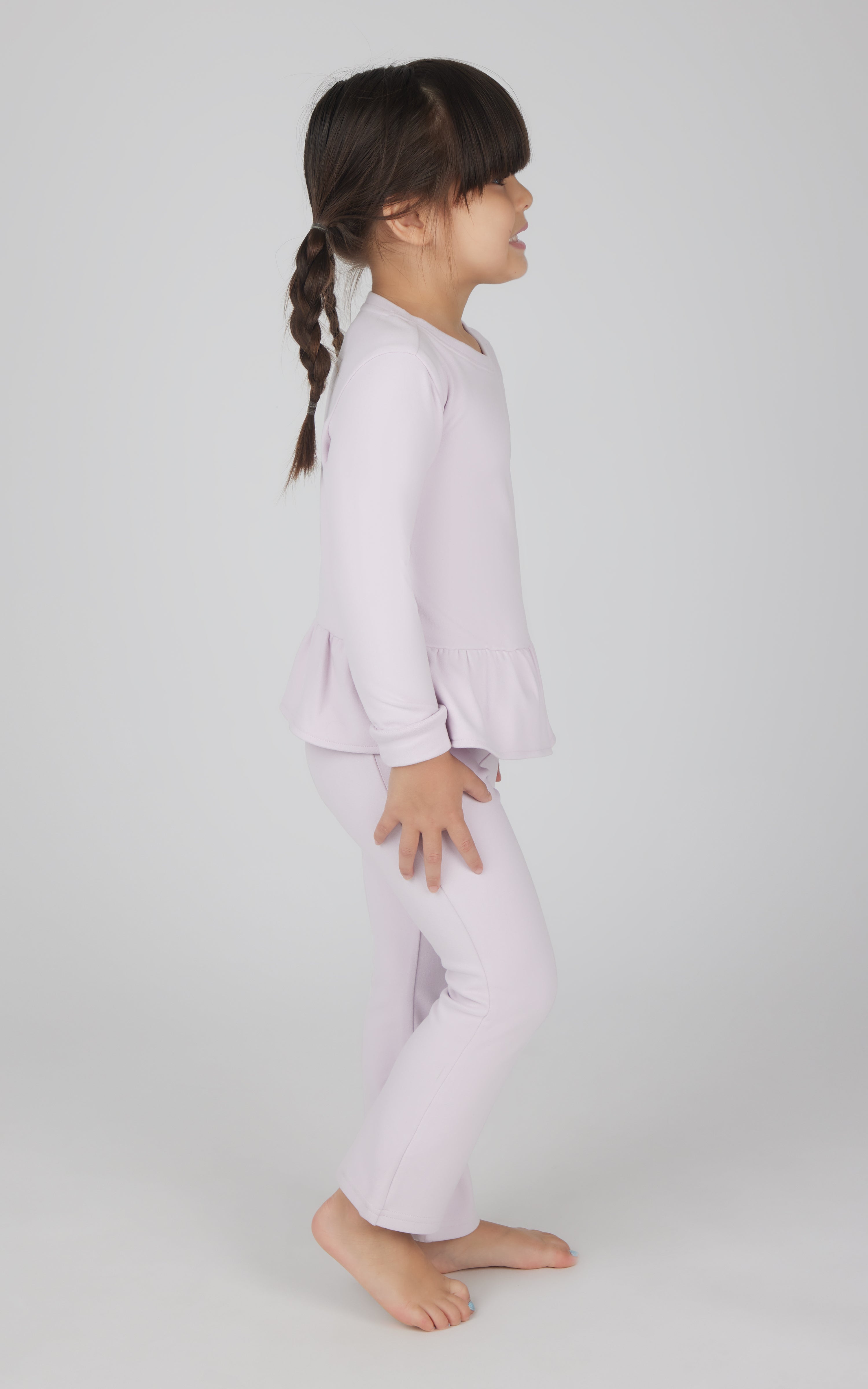Toddler girl wearing light pink melange pullover top with ruffled hem and matching flare leg pants.
