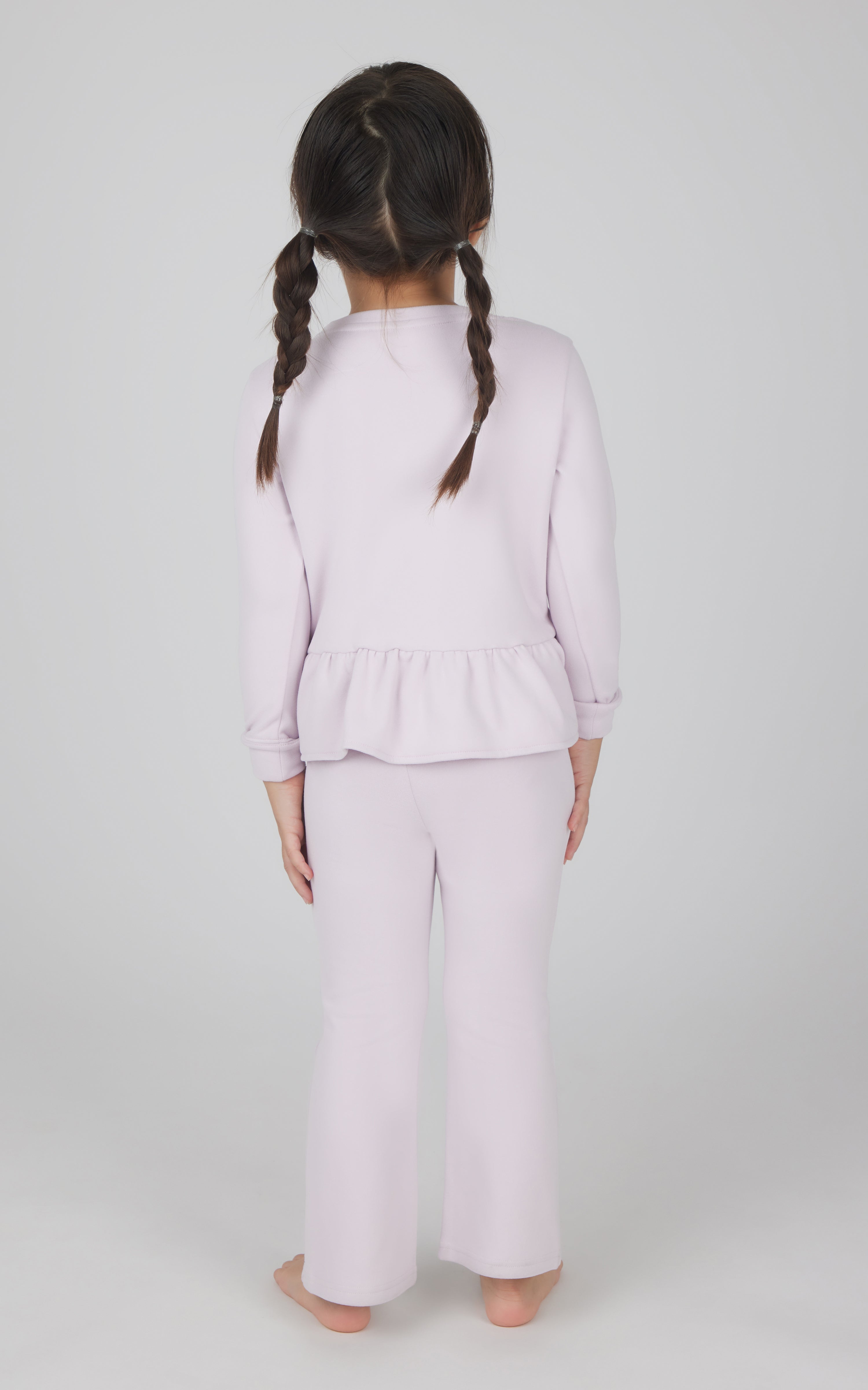 Toddler girl wearing light pink melange pullover top with ruffle hem and matching flare leg pants.