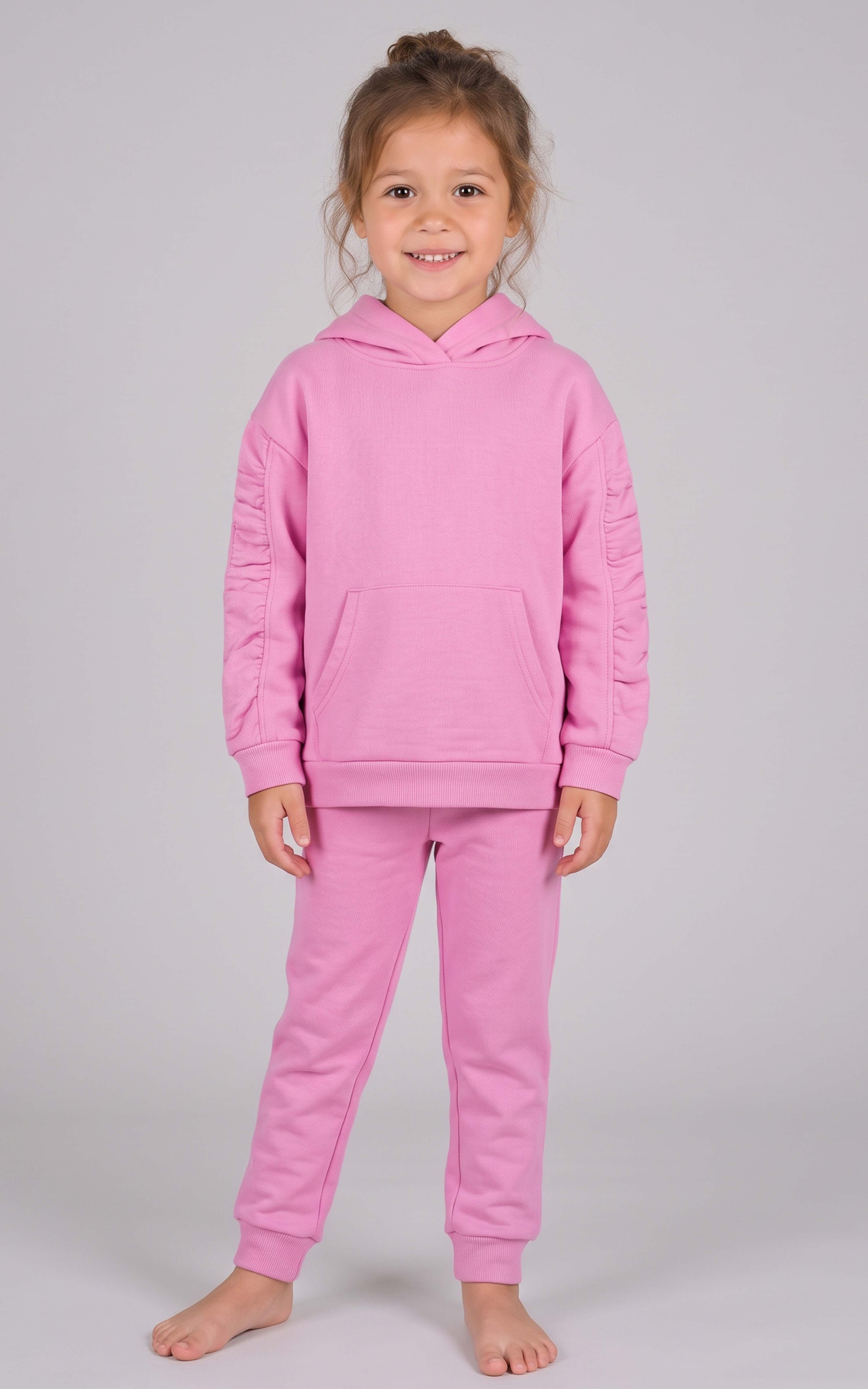 Toddler girl modeling a pink brushed terry hoodie and matching tapered joggers with a drawstring waist.