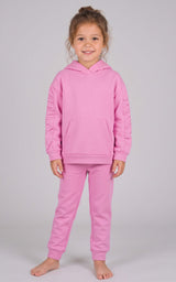 Toddler girl modeling a pink brushed terry hoodie and matching tapered joggers with a drawstring waist.