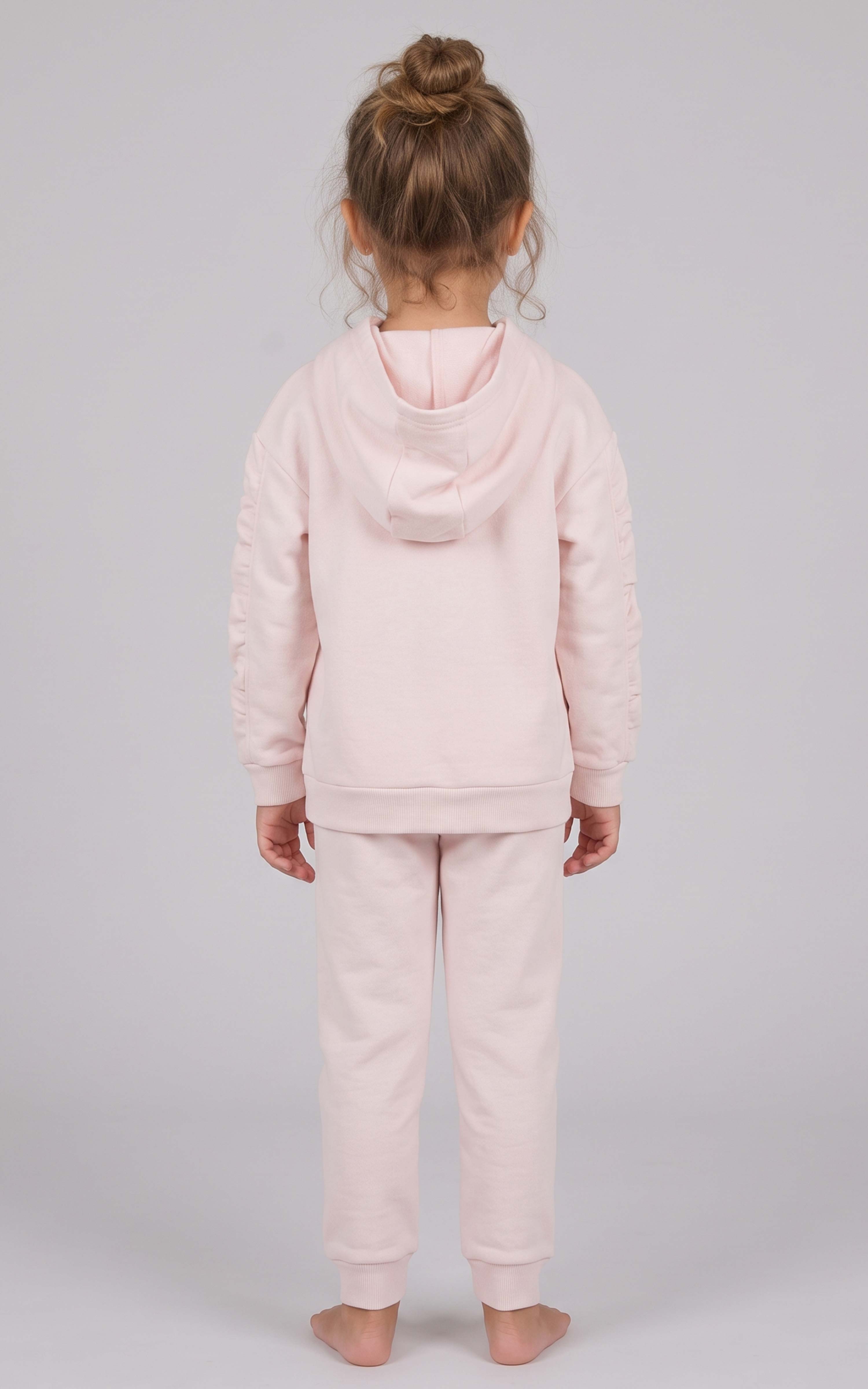 Back view of a toddler girl wearing a pale pink brushed terry hoodie and tapered joggers set.