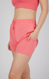 Women's sunkissed coral active shorts with elastic waistband and side pockets, paired with matching cropped top.