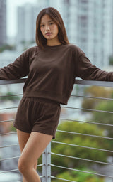 Chocolate torte plush rib long sleeve top with matching lounge shorts on model outdoors.
