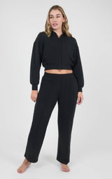 Woman wearing a black cropped zip-up hoodie and matching wide-leg pants in a soft sandwash fabric.