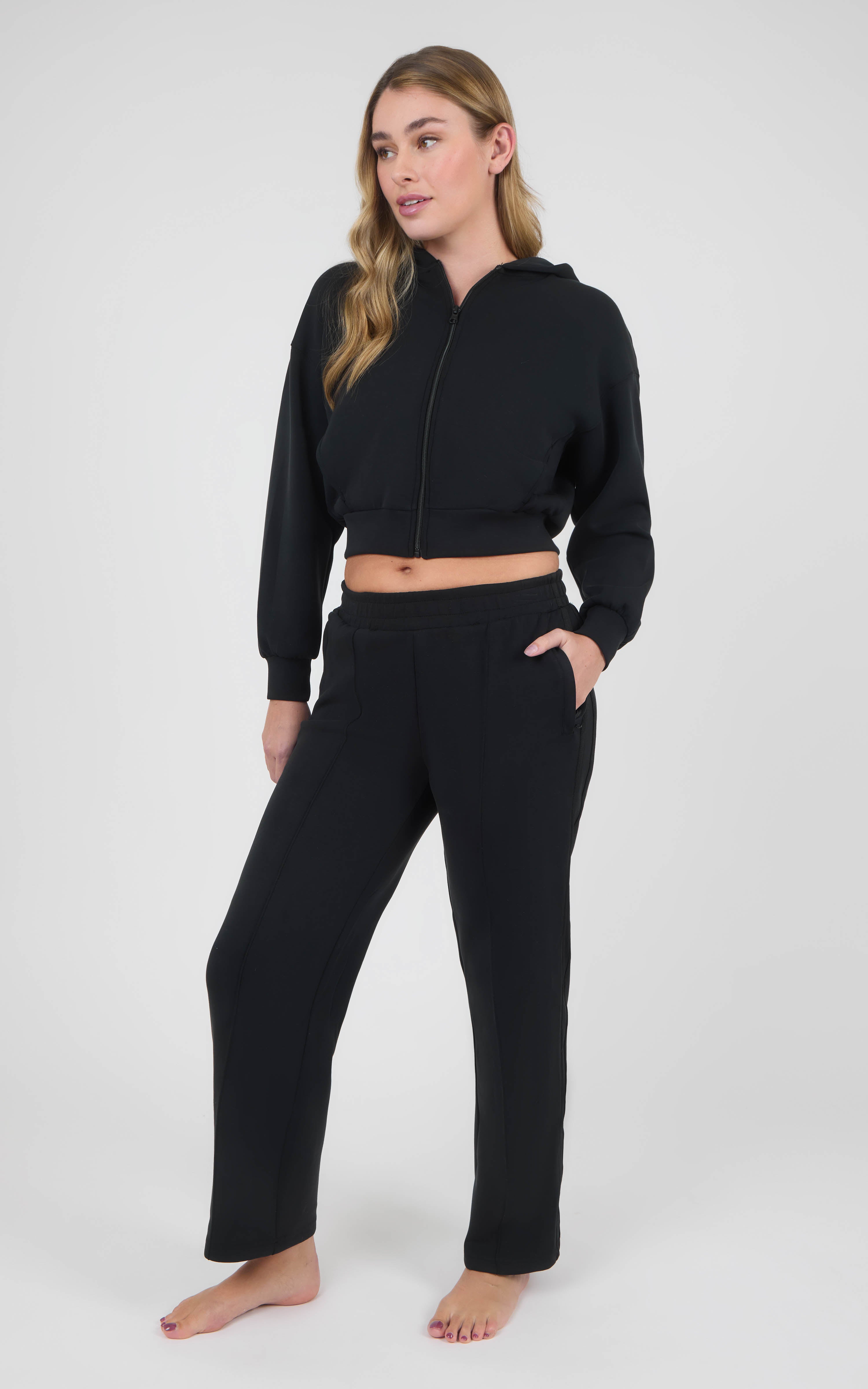 Women's black cropped zip-up hoodie and matching straight-leg pants in a soft sandwash finish, with front pockets.
