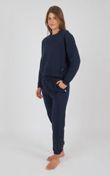 Woman wearing navy blue long-sleeve pullover and matching pintuck jogger pants with pockets.