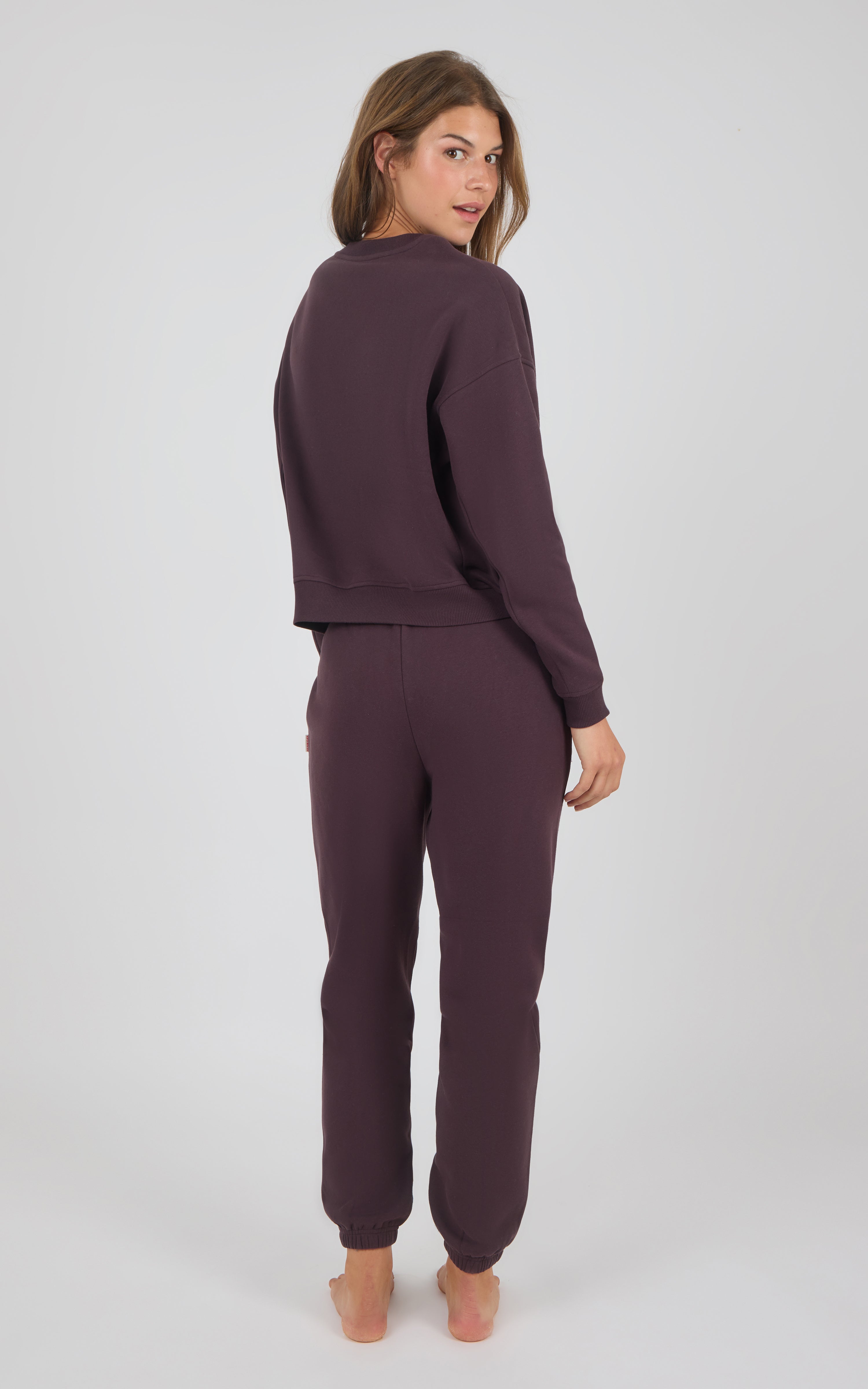 Woman wearing a fitted dark plum long-sleeve top and matching jogger pants with cuffed ankles.