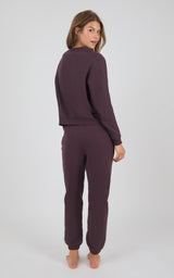 Woman wearing a fitted dark plum long-sleeve top and matching jogger pants with cuffed ankles.