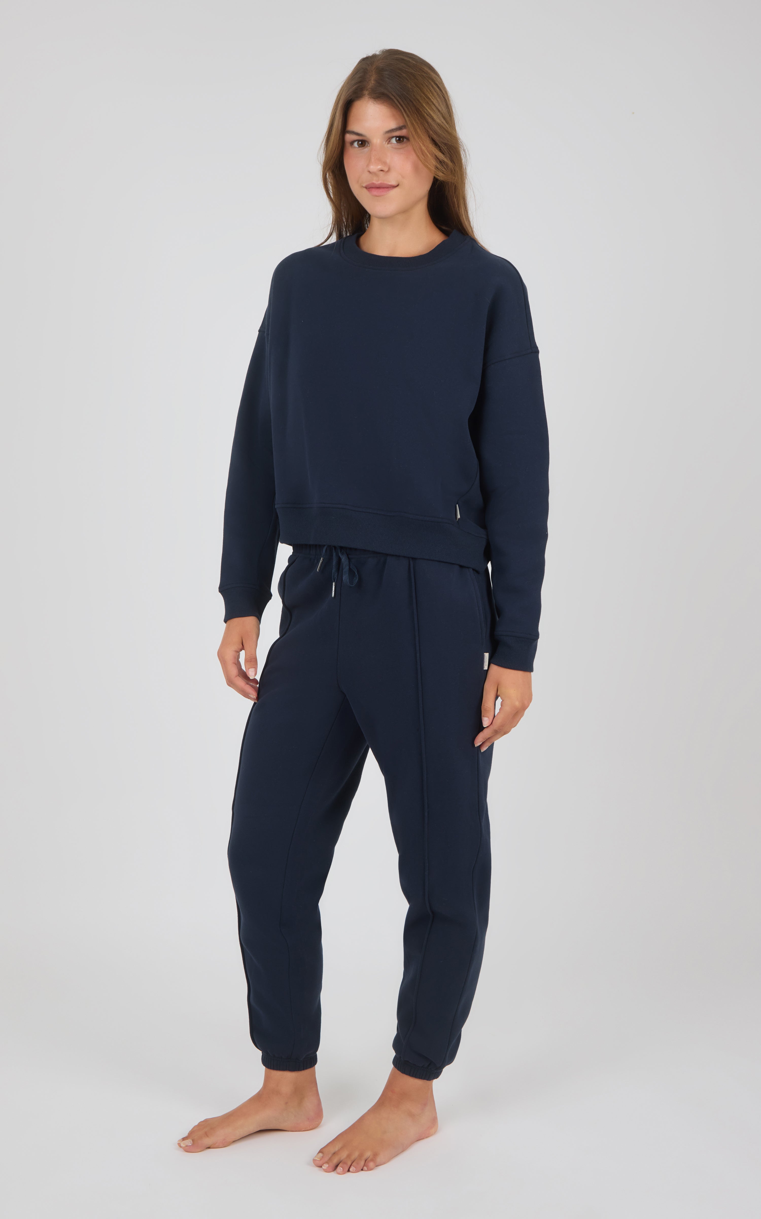 Navy blue crewneck sweatshirt and matching pintuck jogger pants loungewear set on model.