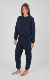 Navy blue crewneck sweatshirt and matching pintuck jogger pants loungewear set on model.