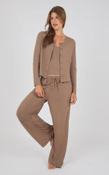 A woman modeling a matching lounge set consisting of a cropped button-front cardigan, a ribbed tank top, and wide-leg drawstring pants in a taupe brown color, set against a plain light gray studio background.