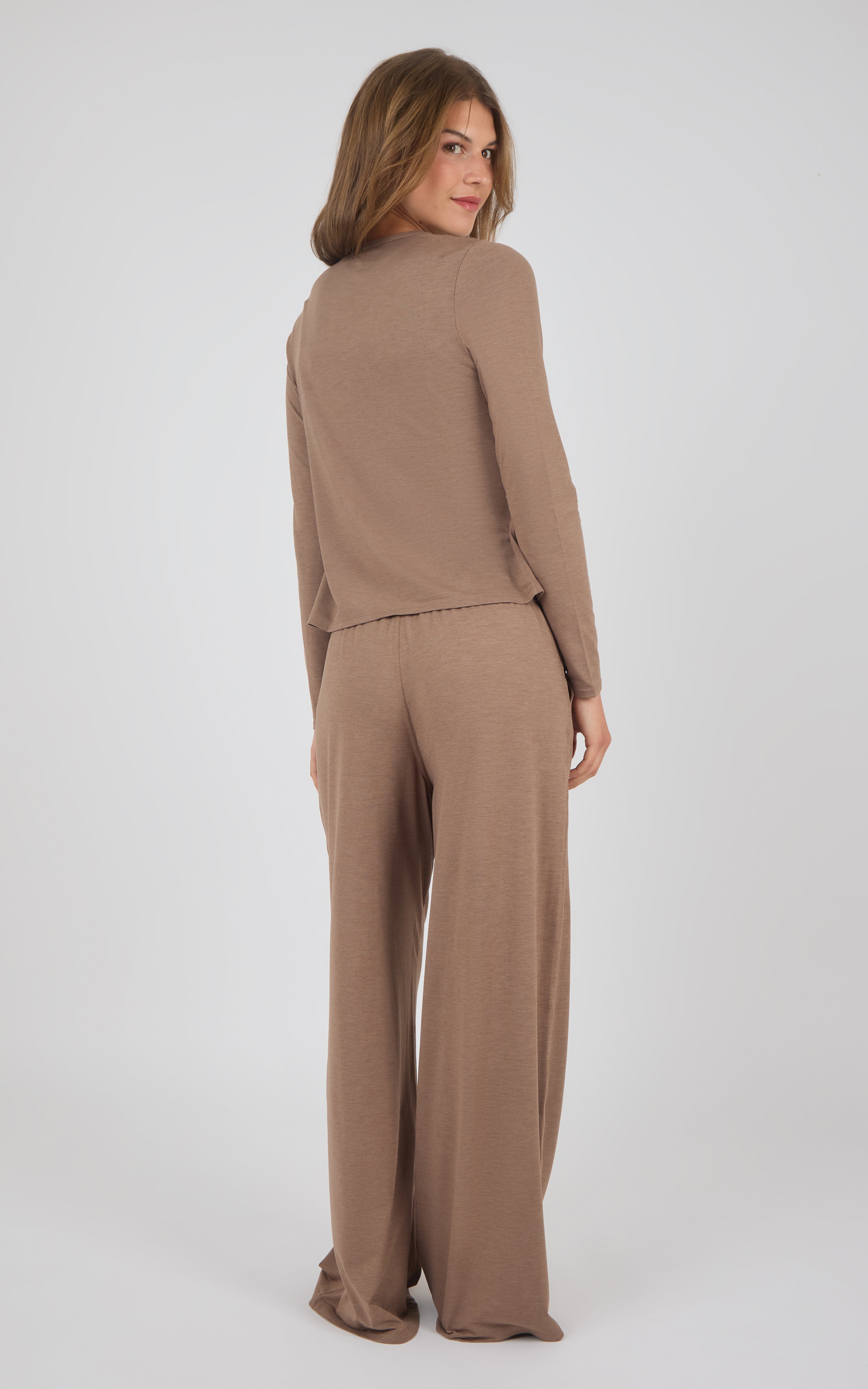 A woman modeling a matching two-piece lounge set in a warm taupe-brown color, photographed from the back against a light gray studio background.