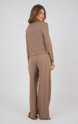 A woman modeling a matching two-piece lounge set in a warm taupe-brown color, photographed from the back against a light gray studio background.
