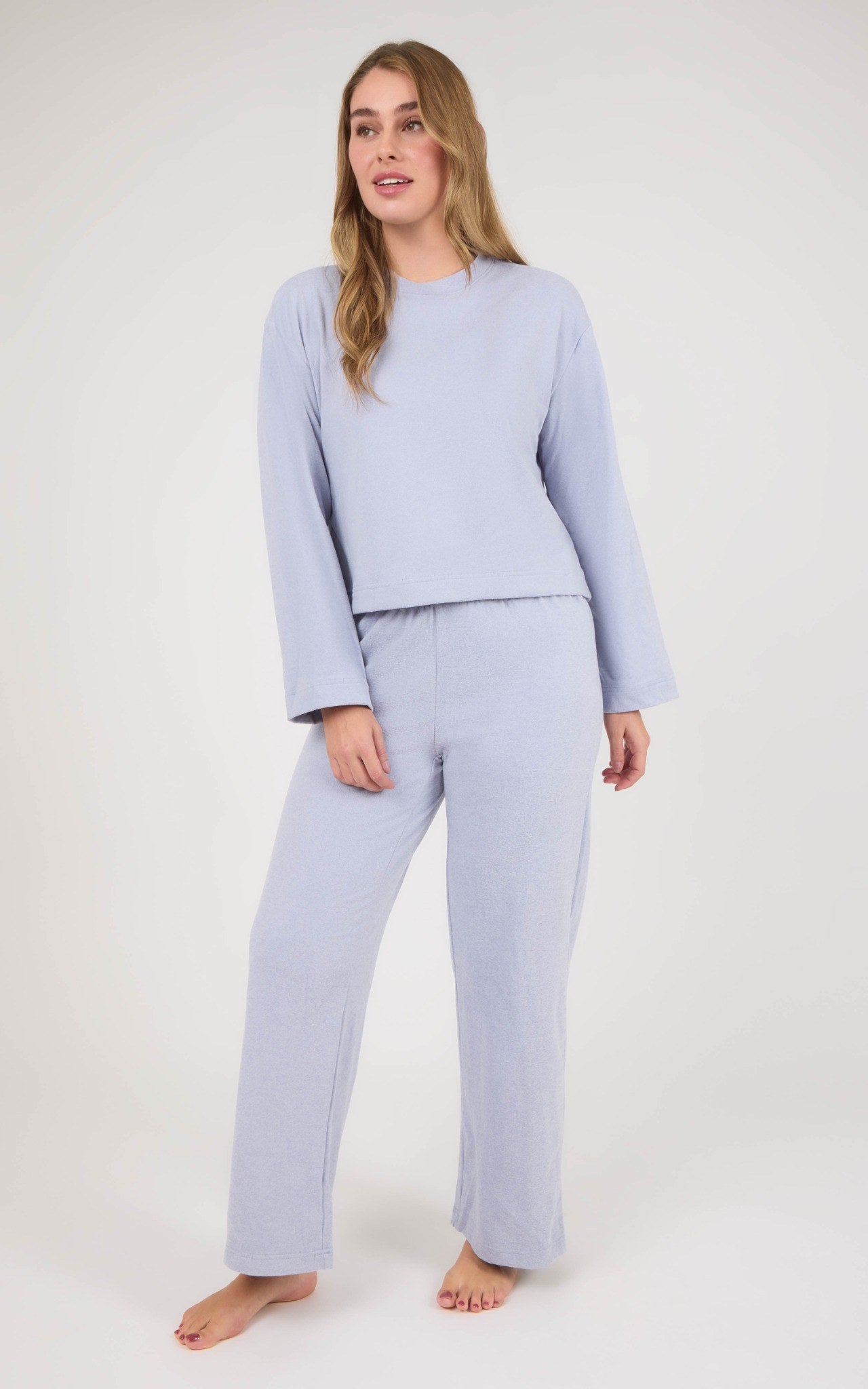 Model wearing a light lavender marled knit set with a boxy cropped long-sleeve top and straight-leg pants.