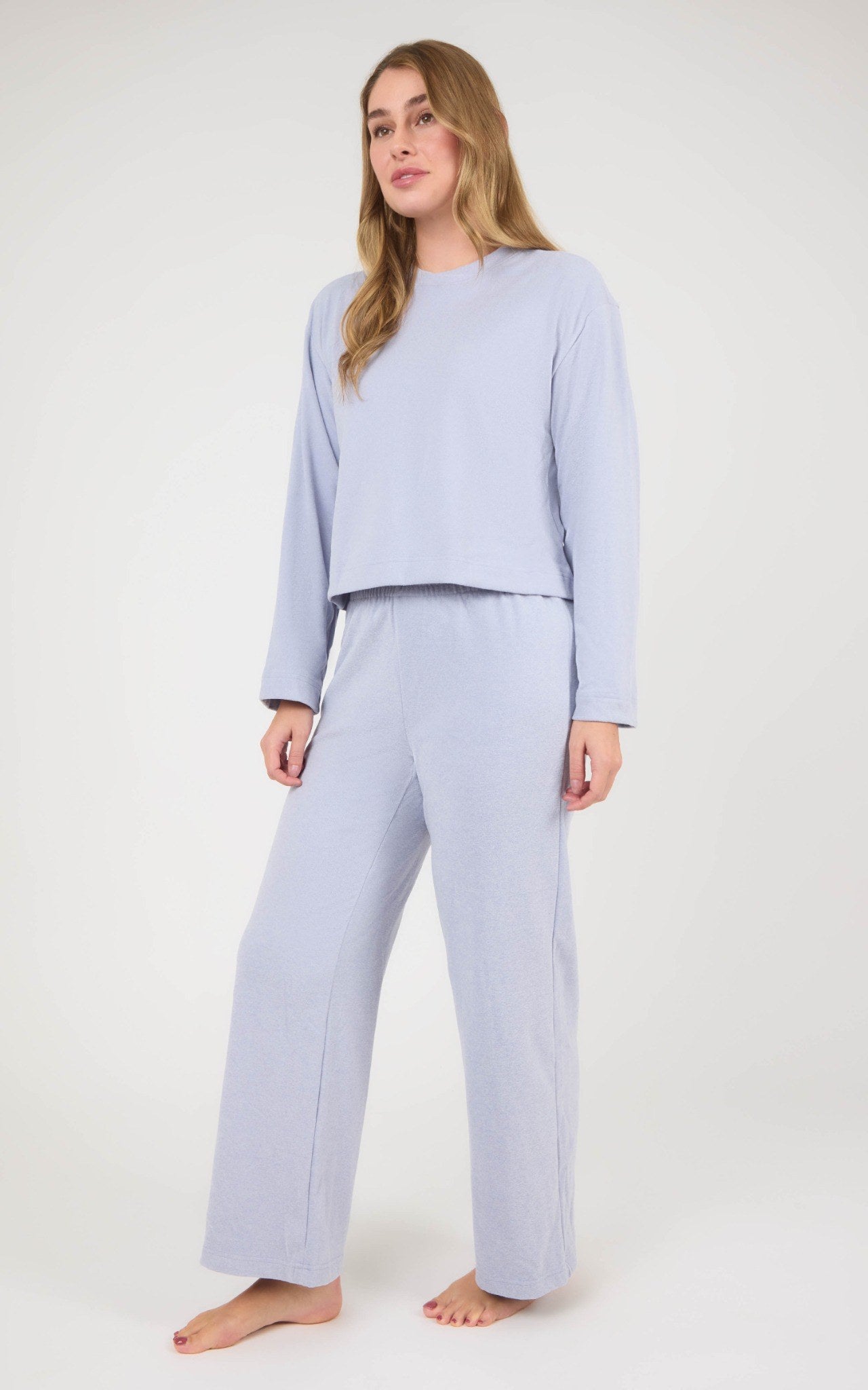 Model wears a pale blue marled lounge set with a boxy cropped long-sleeve top and straight-leg pants.