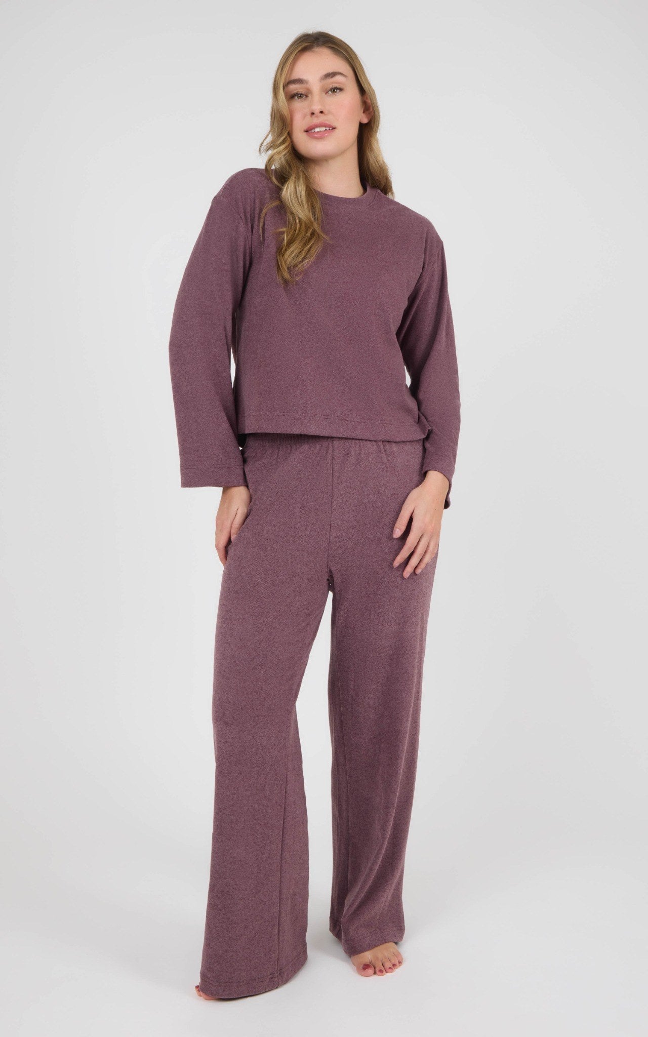 Woman wearing a mauve marled lounge set with a boxy cropped long-sleeve top and straight-leg pants.