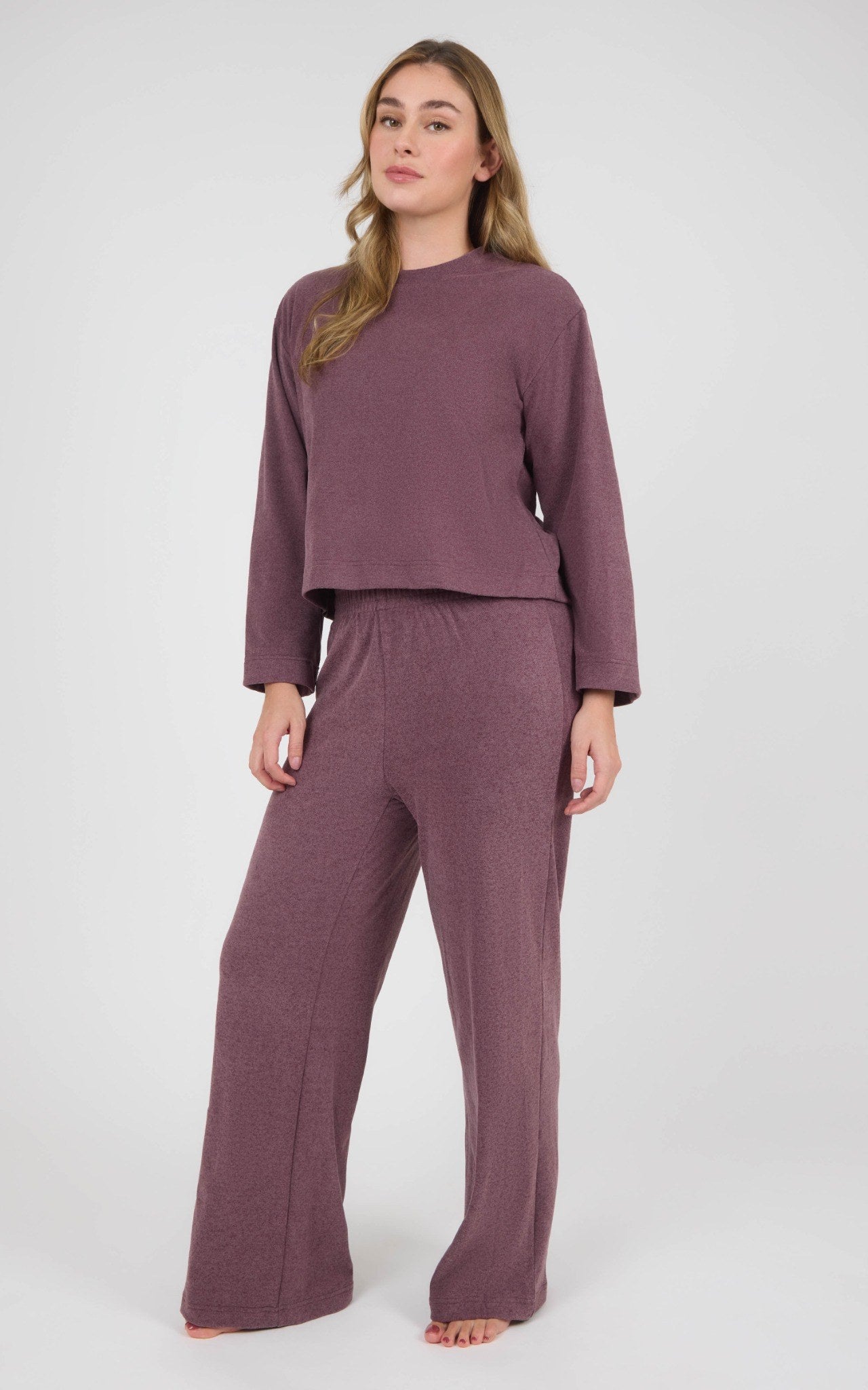 Woman wearing a mauve marled knit set with a boxy cropped long-sleeve top and wide-leg pants.
