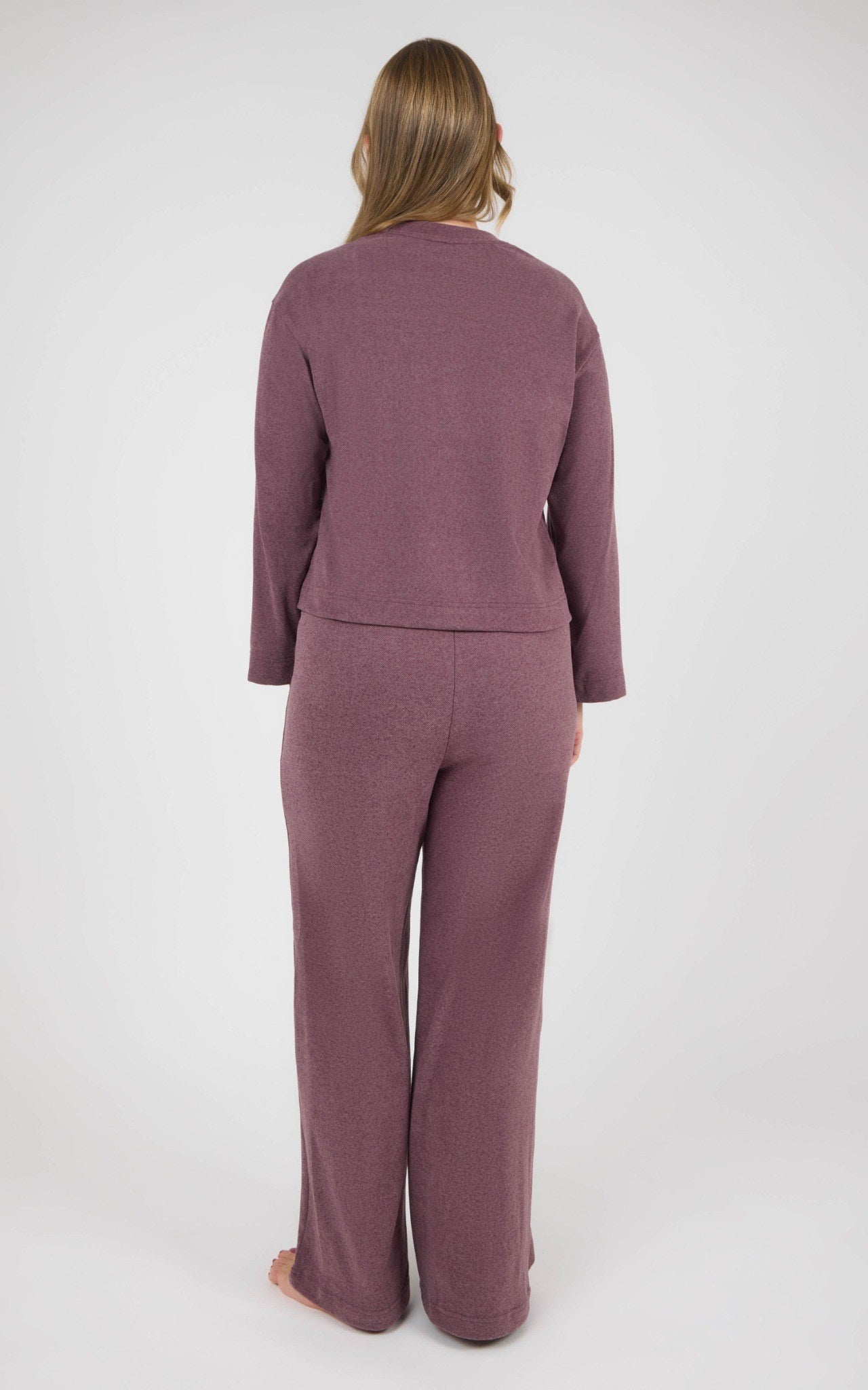 Back view of a woman wearing a mauve marled knit set with a boxy long-sleeve top and straight-leg pants.