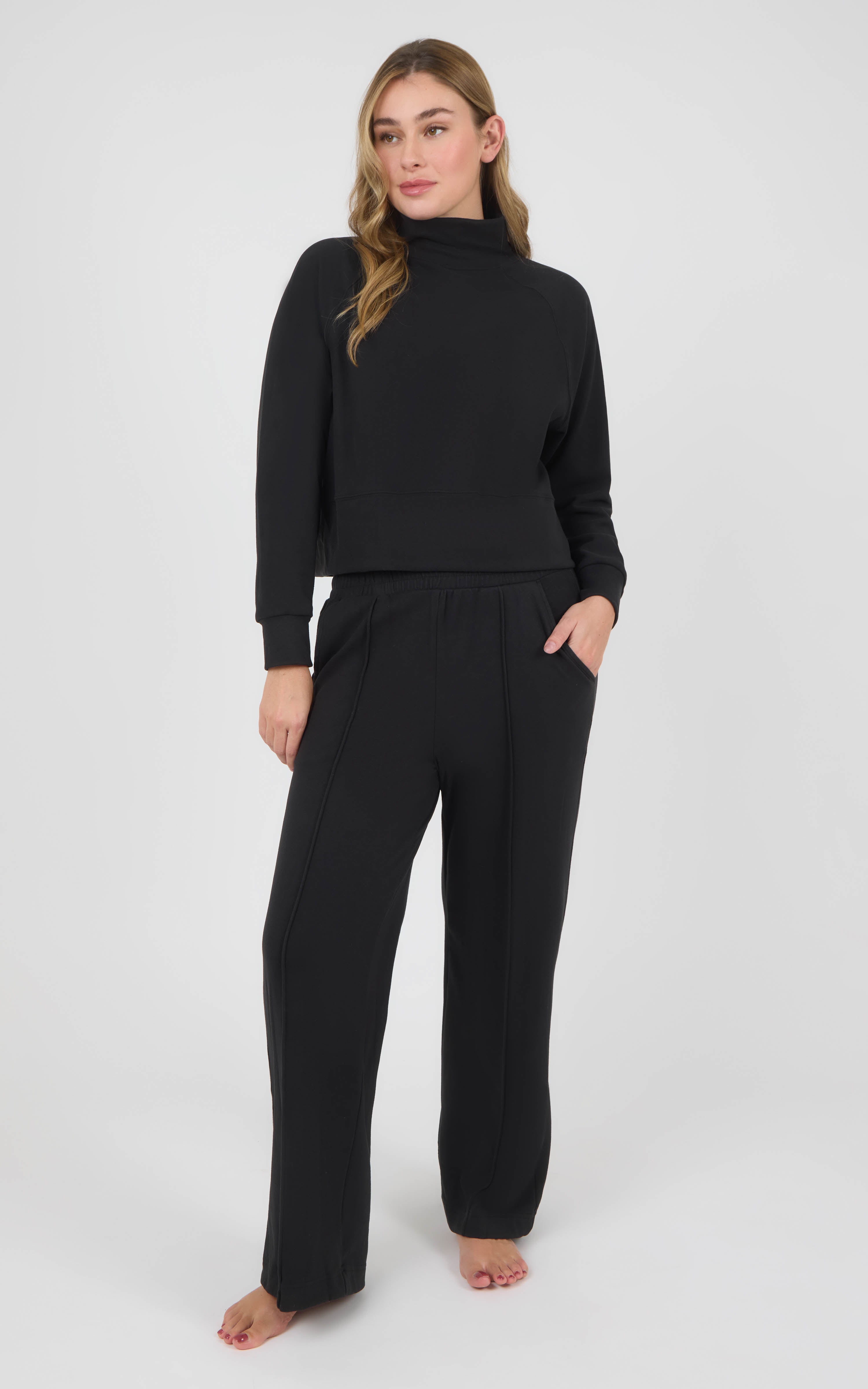 Woman wearing a black long-sleeve pullover and matching wide-leg pants in textured marled pique fabric.