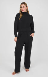 Woman wearing a black long-sleeve pullover and matching wide-leg pants in textured marled pique fabric.
