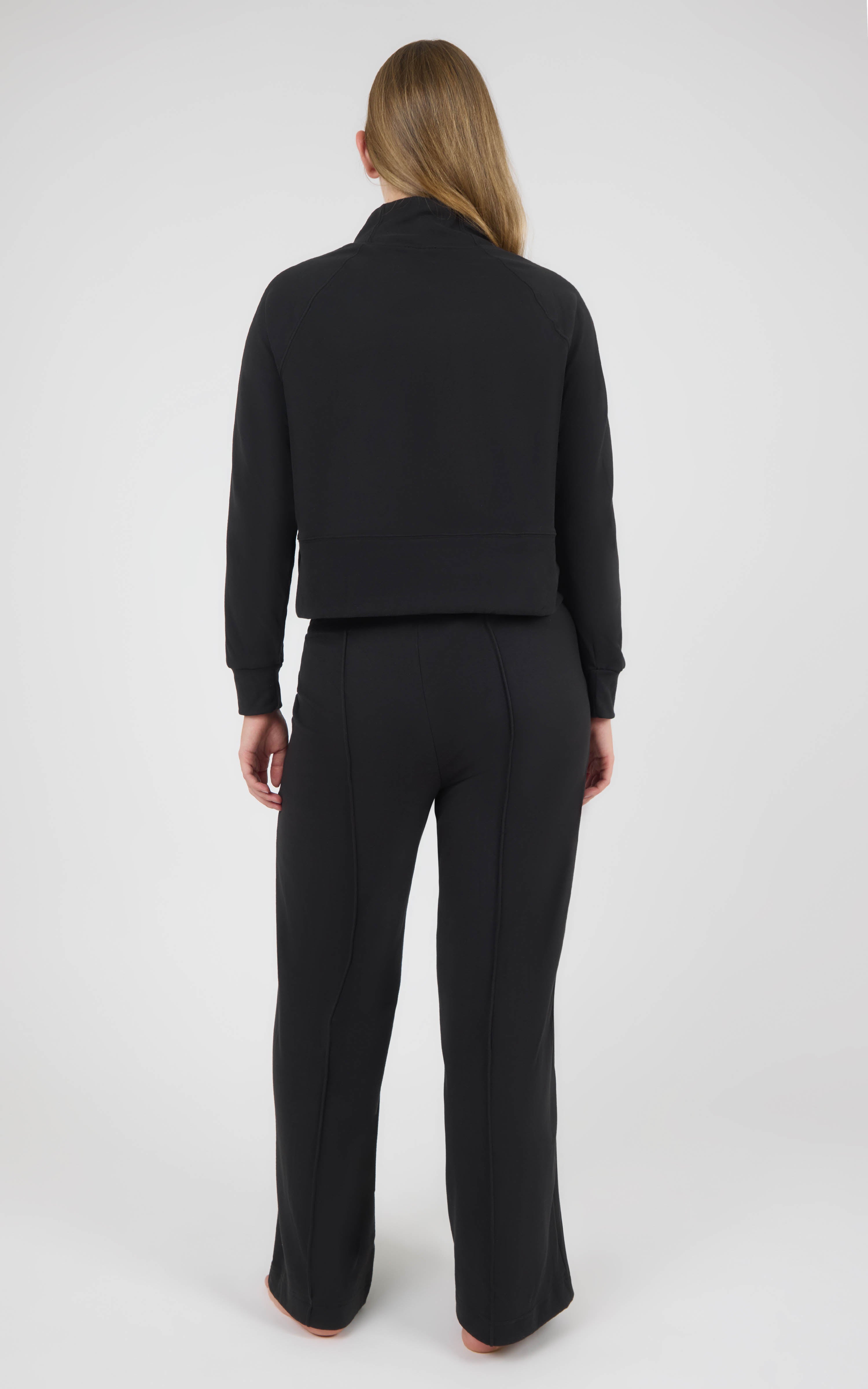 Back view of a black long-sleeve pullover and matching wide-leg pants in textured marled pique fabric.