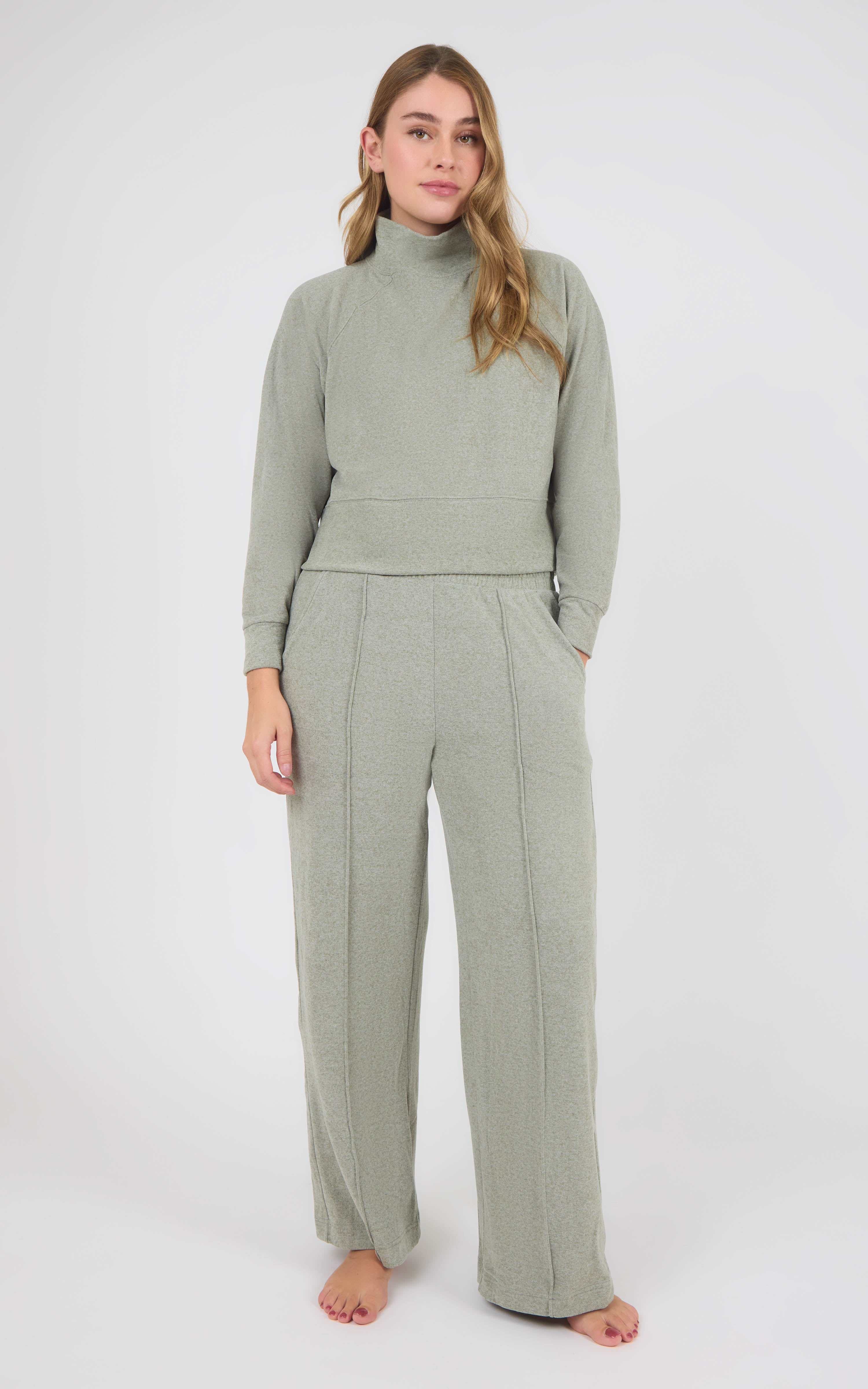 Woman wearing a sage gray marled knit pullover with raglan sleeves and matching pintuck wide-leg pants.