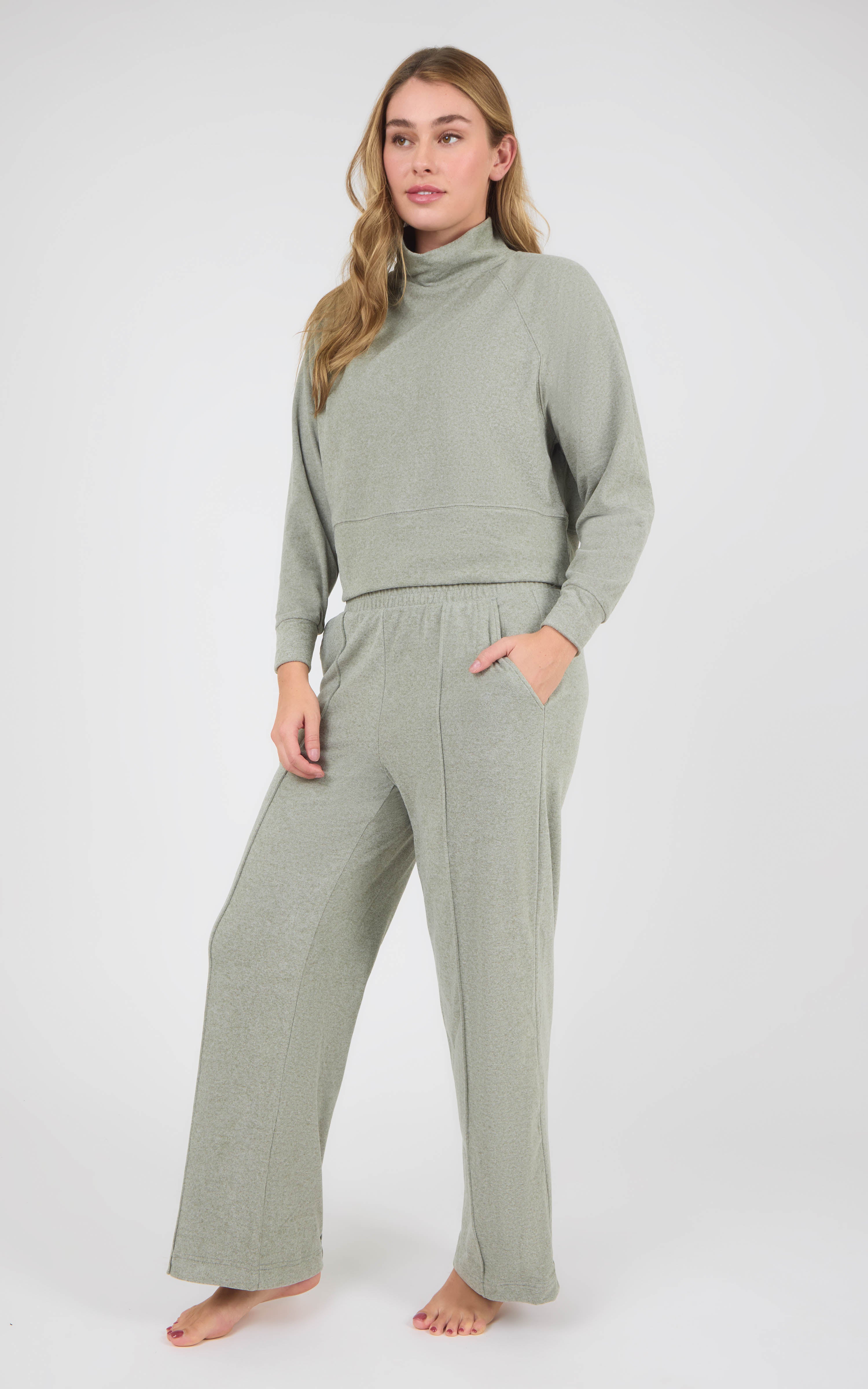 Woman wearing a sage gray marled knit pullover with raglan sleeves and matching pintuck wide-leg pants.