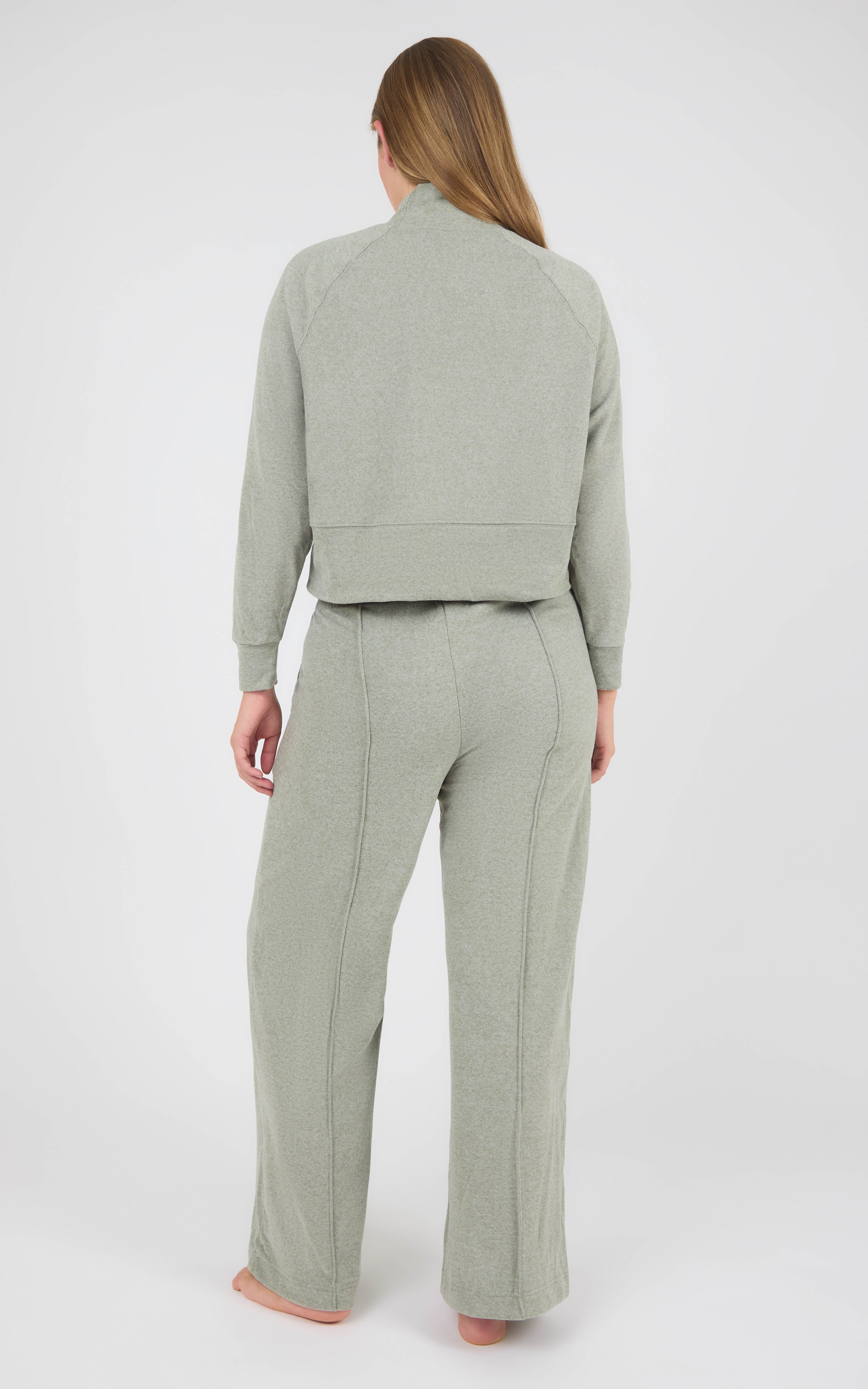 Back view of a woman wearing a light gray marled knit lounge set with a long-sleeve pullover and wide-leg pants.