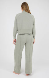 Back view of a woman wearing a light gray marled knit lounge set with a long-sleeve pullover and wide-leg pants.
