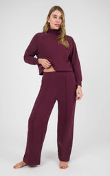 Woman wearing a burgundy marled pique pullover with long sleeves and matching wide-leg pants, styled barefoot.