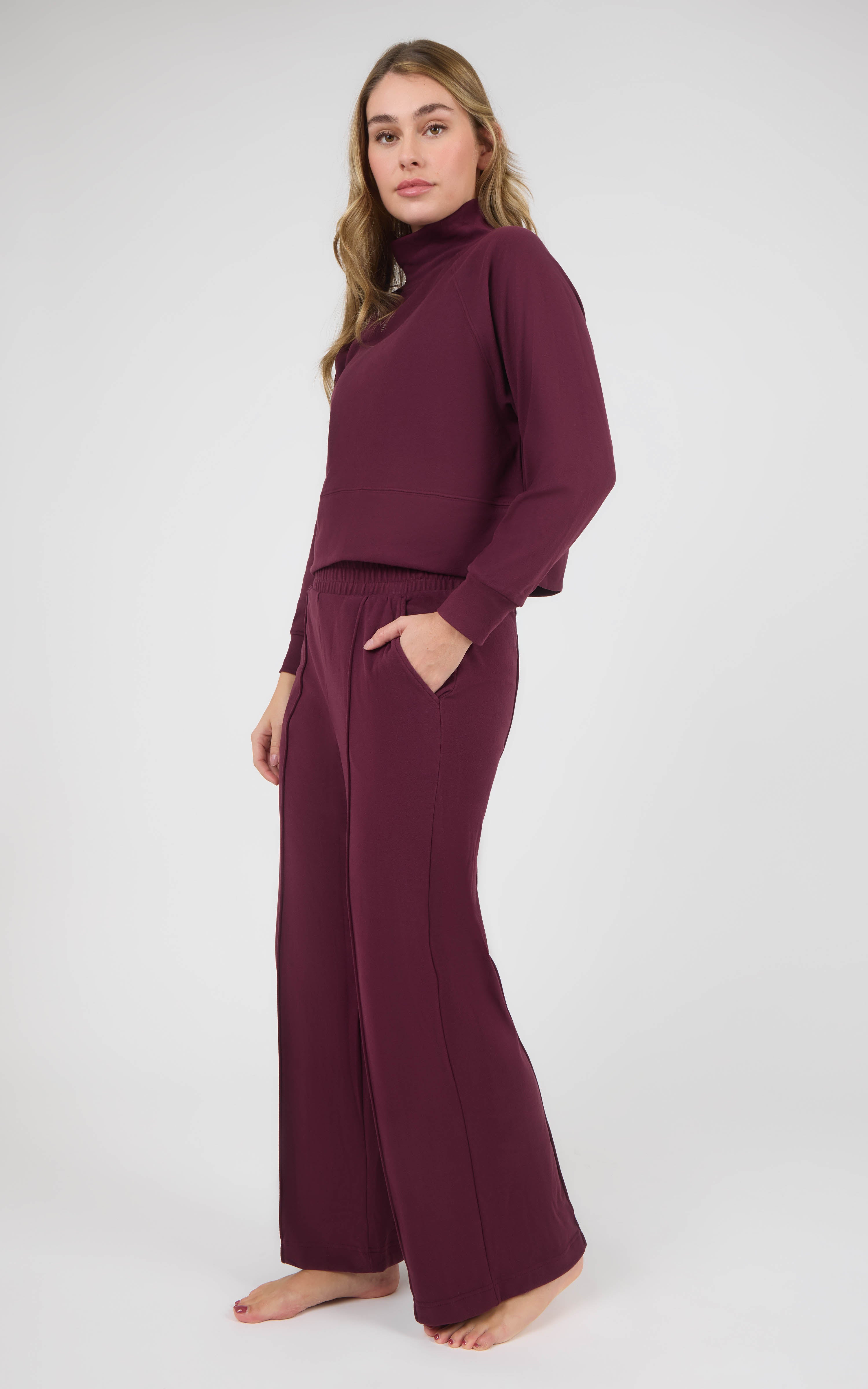 Woman wearing a burgundy long-sleeve pullover and matching wide-leg pants in marled pique fabric.