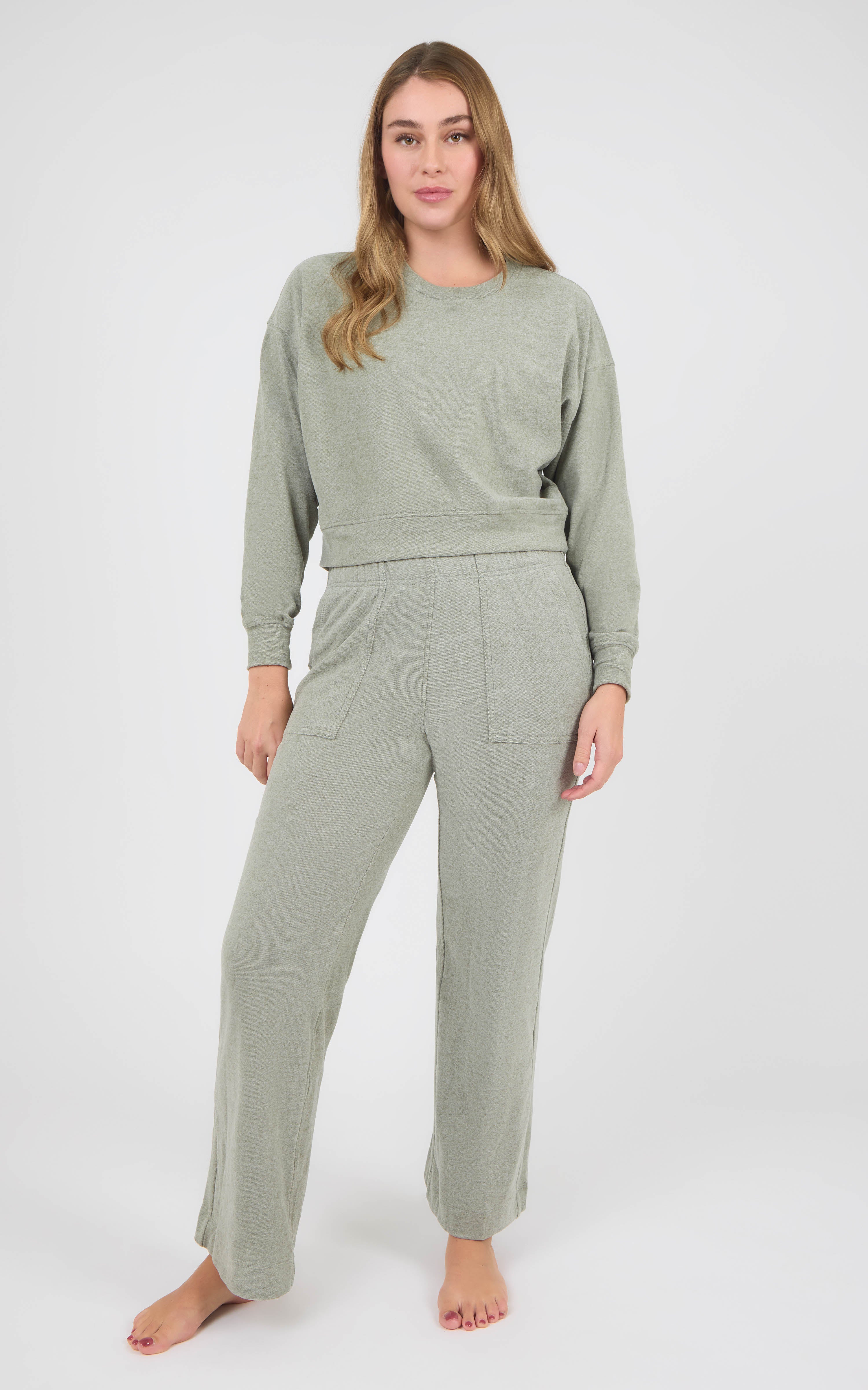 Woman wearing a sage green marled pique lounge set with a crew-neck long-sleeve top and wide-leg pants.