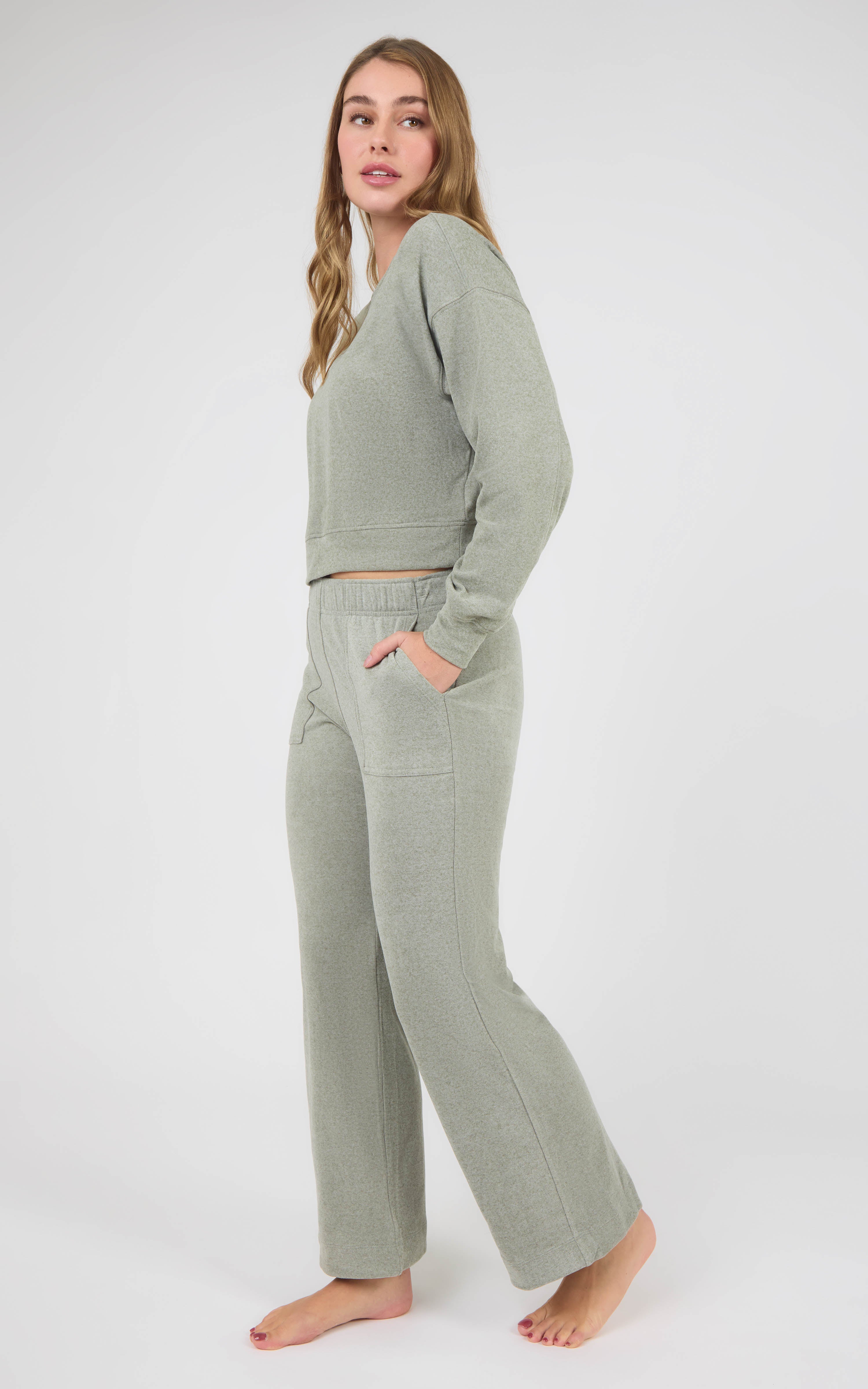 Woman wearing a sage marled pique crewneck pullover and matching wide-leg pants with side pockets.