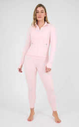Woman wearing a pale pink fitted zip-front jacket and matching ankle-length leggings with a V-shaped waistband.