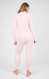 Back view of a woman wearing a pale pink fitted jacket and matching ankle-length leggings.